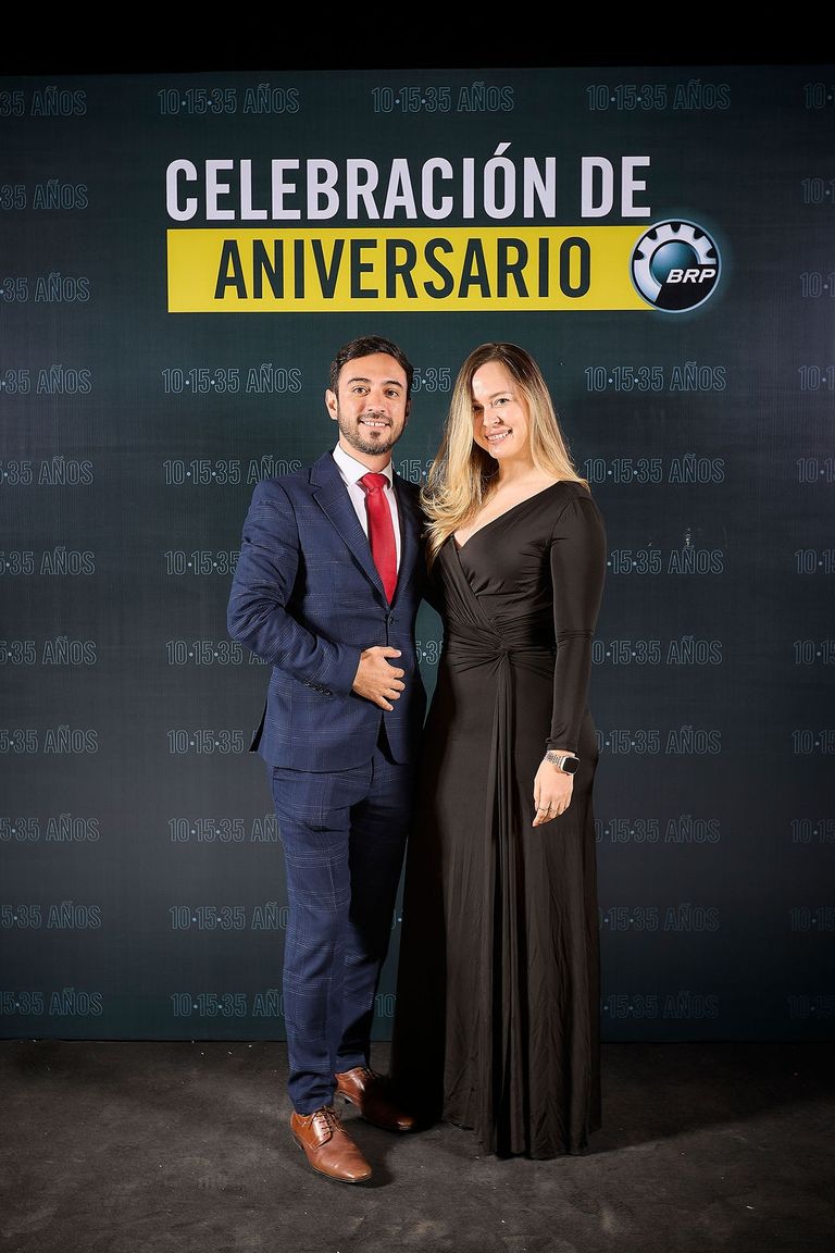 Couple in evening dress in front of the BRP Anniversary Celebration wall reading 10·15·35 years