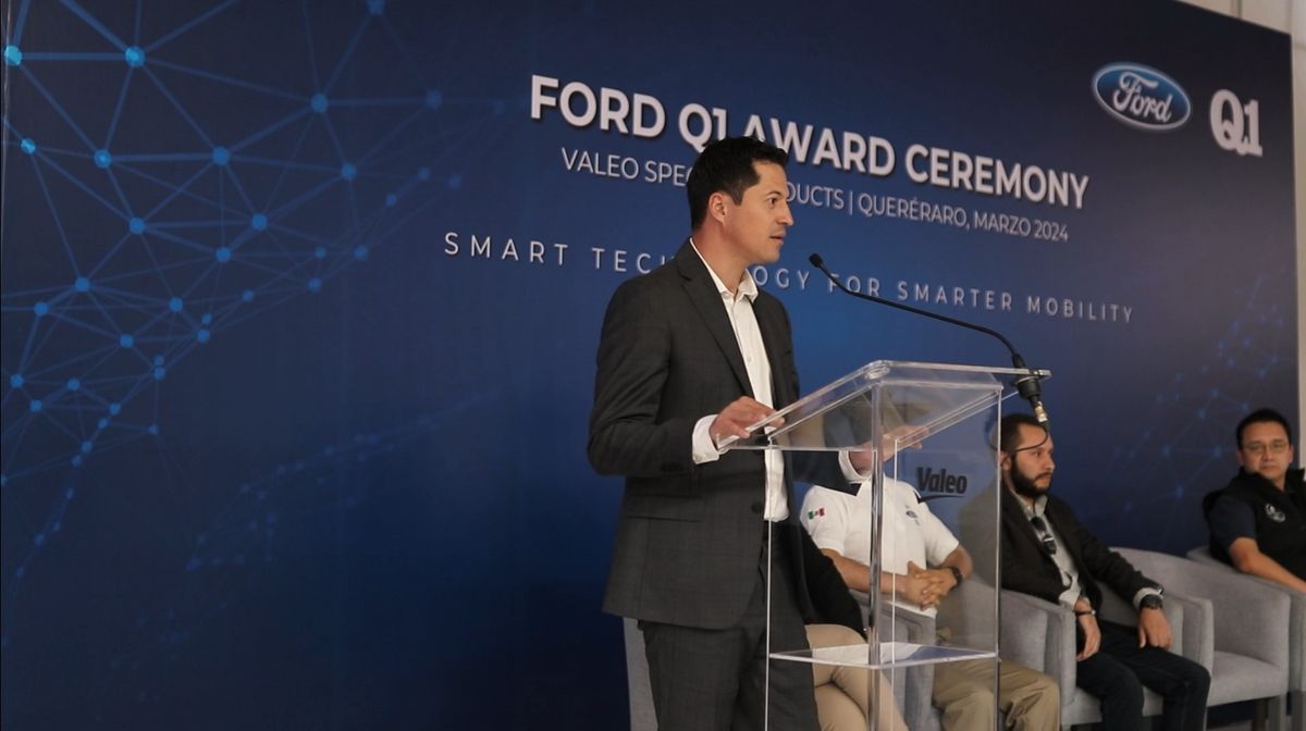 Executive speaking at an acrylic lectern in front of the Ford Q1 Award Ceremony backdrop for Valeo Specialty Products in Querétaro